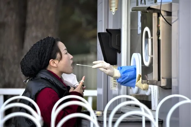 A woman has her throat swabbed for a COVID-19 test at a coronavirus testing site in Beijing, Tuesday, November 1, 2022. Shanghai Disneyland was closed and visitors temporarily kept in the park for virus testing, the city government announced, while social media posts said some amusements kept operating for guests who were blocked from leaving. (Photo by Mark Schiefelbein/AP Photo)