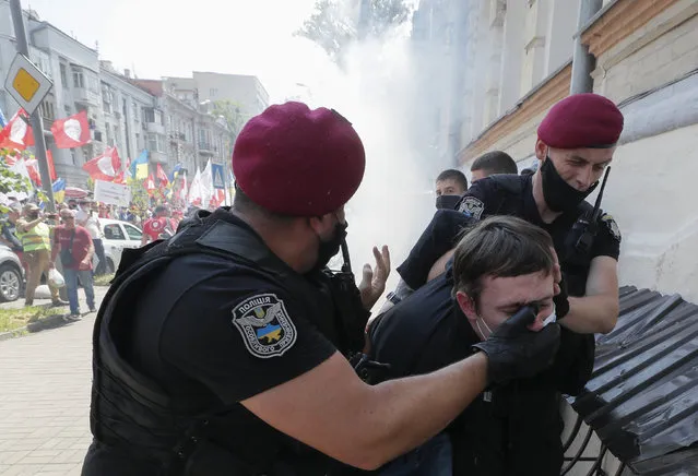 Ukrainian police officers detain a far-right militant who had previously allegedly attacked members and supporters of the Party of Shariy taking part in a protest rally in front of the Presidential Office in Kiev, Ukraine, 17 June 2020. The activists supporting the conservative Eurosceptic party led by populist journalist Anatoly Shariy gathered under the slogan “The dumb president” as they lambasted Ukrainian President Volodymyr Zelensky for what they perceive as his failure to implement his election campaign promises. (Photo by Sergey Dolzhenko/EPA/EFE)