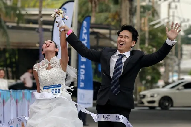 Naree Phavasanta, left, and Suparoek Charoenphol celebrate while crossing the finish line to win the Running of the Brides in Bangkok, Thailand, December 2, 2017. (Photo by Athit Perawongmetha/Reuters)