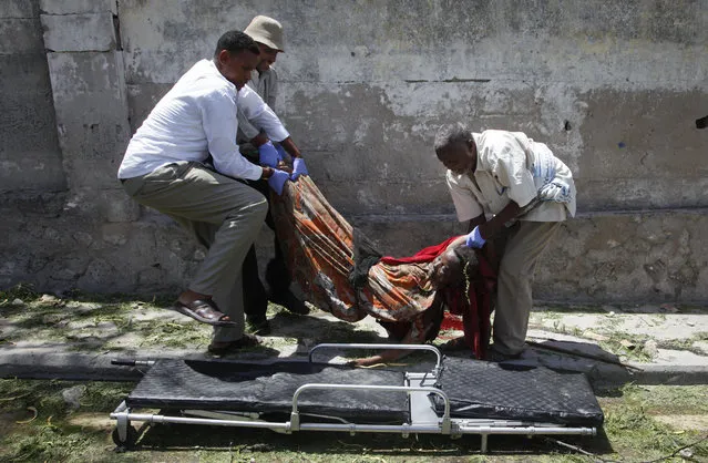 Somali men carry away the body of a woman who was killed by a blast near the presidential palace in the capital Mogadishu, Somalia Tuesday, August 30, 2016. (Photo by Farah Abdi Warsameh/AP Photo)