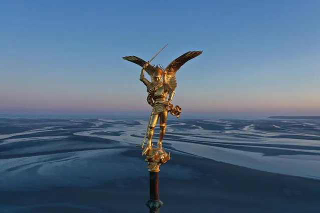 An aerial photograph taken on May 25, 2020 shows the statue of Saint Michael and the dragon, at the top of the spire of Mont Saint-Michel Abbey, in Normandy, northwestern France, during the sunrise. Since 1979 the site of the Mont Saint-Michel and its bay is a UNESCO world heritage site. (Photo by Damien Meyer/AFP Photo)