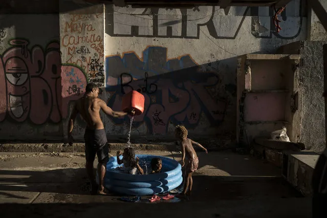 In this September 11, 2017 photo, children play as a man fills a small plastic pool with water at a squatter building that used to house the Brazilian Institute of Geography and Statistics (IBGE) in the Mangueira slum of Rio de Janeiro, Brazil. Economists say that high unemployment and cuts to key social welfare programs could exacerbate some Brazilians' slide back into poverty. (Photo by Felipe Dana/AP Photo)