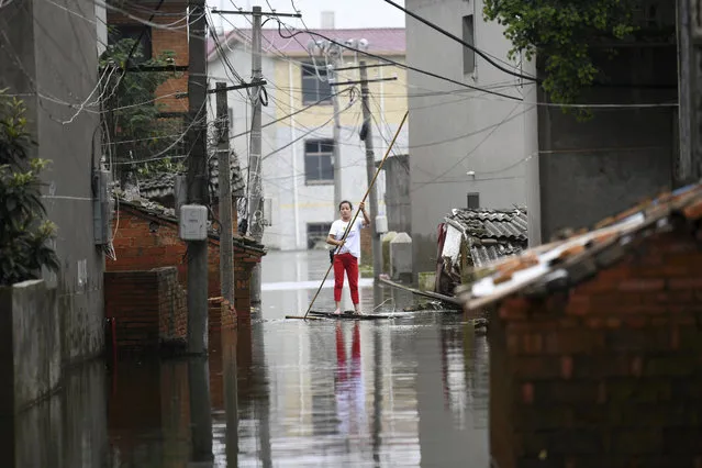 A woman pushes a makeshift raft down a flooded alleyway in a village in Yongxiu in central eastern China's Jiangxi province, Thursday, July 16, 2020. Engorged with more heavy rains, China's mighty Yangtze River is cresting again, bringing fears of further destruction. (Photo by Chinatopix via AP Photo)