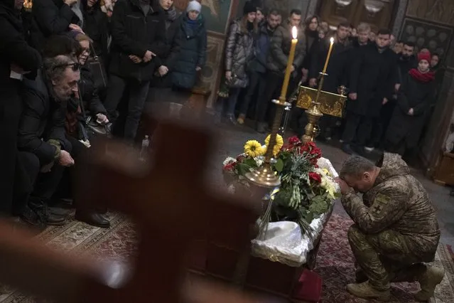 Relatives, friends, and comrades mourn next to the coffin of Ukrainian serviceman Sergii Myronov, killed fighting Russian troops in Donetsk region, during a funeral ceremony at St. Michael's Golden-Domed Monastery in Kyiv, Ukraine, Wednesday, November 23, 2022. (Photo by Andrew Kravchenko/AP Photo)