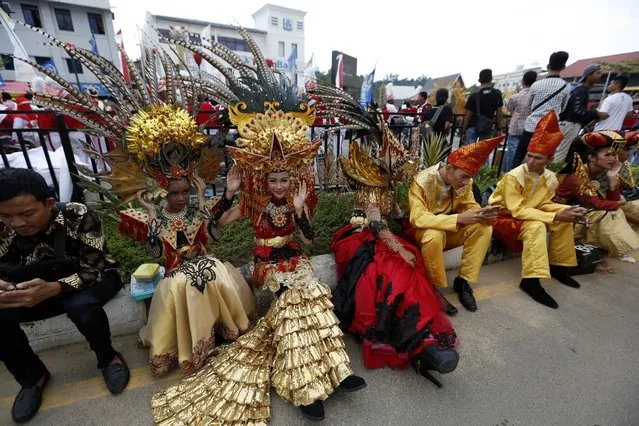 Indonesian models wearing colorful costumes take a rest before a parade during the Batam Island International Culture Festival in Batam Island, Indonesia, 16 December 2017. (Photo by Hotli Simanjuntak/EPA/EFE)