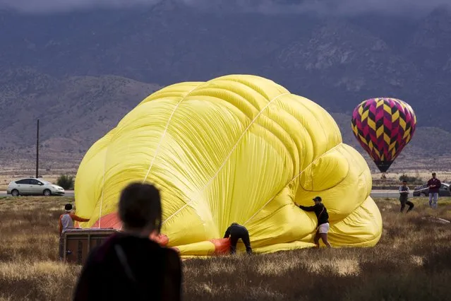 Crew members work to secure a hot air balloon after landing during the 2015 Albuquerque International Balloon Fiesta in Albuquerque, New Mexico, October 4, 2015. (Photo by Lucas Jackson/Reuters)