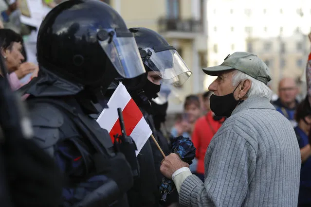 An elderly protester speaks to a policeman holding an old Belarusian national flag in front of riot police blocked Independence Square in Minsk, Belarus, Thursday, August 27, 2020. (Photo by Sergei Grits/AP Photo)