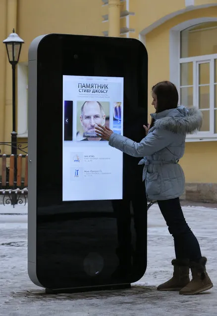 In this file photo dated Thursday, January 10, 2013, a girl touches the screen showing a portrait of Steve Jobs on the recently erected memorial to late Apple Corp. co-founder in the courtyard of the Techno Park of the St. Petersburg National Research University of Information Technologies, Mechanics and Optics (ITMO University) in St. Petersburg, Russia. (Photo by Dmitry Lovetsky/AP Photo)