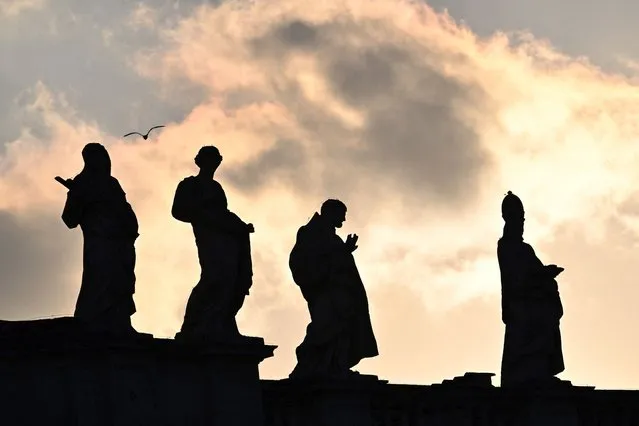 A photo shows statues on a colonnade, seen in silhouette, on St Peter's square in the Vatican, during the lying in state of Pope Emeritus Benedict XVI, on January 4, 2023. Benedict, a conservative intellectual who in 2013 became the first pontiff in six centuries to resign, died on December 31, 2022, at the age of 95. Thousands of Catholics began paying their respects on January 2, 2023 to former pope Benedict XVI at St Peter's Basilica at the Vatican, at the start of three days of lying-in-state before his funeral. (Photo by Andreas Solaro/AFP Photo)