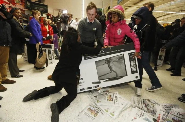 Shoppers wrestle over a television as they compete to purchase retail items on “Black Friday” at an Asda superstore in Wembley, north London November 28, 2014. Britain's high streets, malls and online sites were awash with discounts on Friday as more retailers than ever embraced U.S.-style “Black Friday” promotions, seeking to kickstart trading in the key Christmas period. (Photo by Luke MacGregor/Reuters)