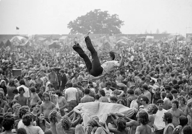 As concert goers wait for the rock music to begin, a group takes part in a blanket toss at the Goose Lake International Music Festival near Jackson, Mich., August 9, 1970. Here a young woman gets tossed in the air. The crowd, numbering around 200,000, seemed to enjoy the three-day event which was free of incident. (Photo by Mark Foley/AP Photo)