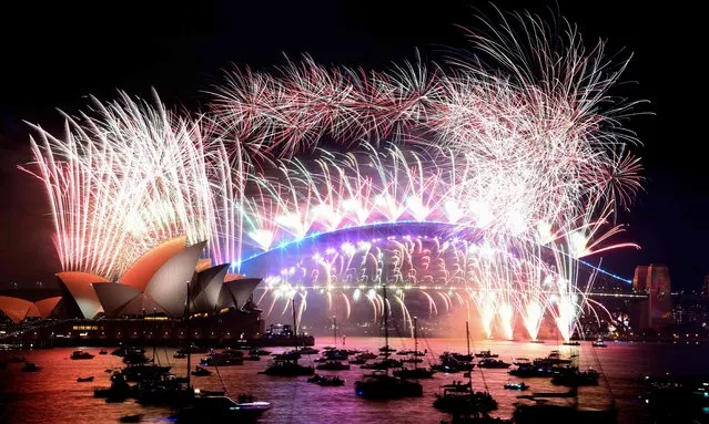 New Year's Eve fireworks light up the sky over Sydney's iconic Harbour Bridge and Opera House (L) during the fireworks show on January 1, 2022. (Photo by David Gray/AFP Photo)
