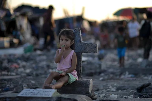 A girl sits next to a tombstone amidst a slum area inside the municipal cemetery in Navotas city, north of Manila October 29, 2015. (Photo by Ezra Acayan/Reuters)