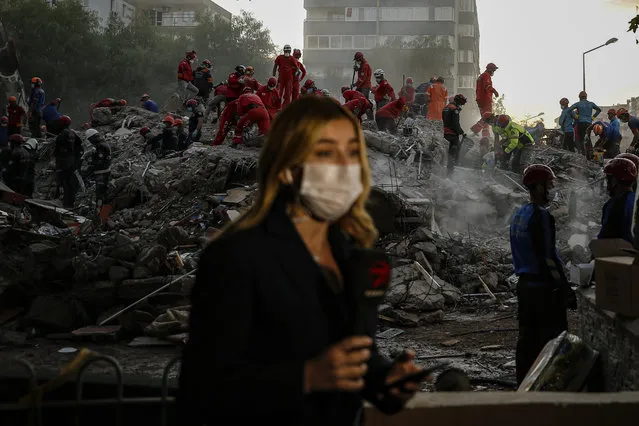 A TV journalist broadcasts from the scene as members of rescue services search for survivors in the debris of a collapsed building in Izmir, Turkey, Monday, November 2, 2020. (Photo by Emrah Gurel/AP Photo)