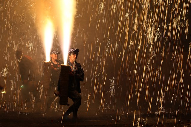 Pyrotechnicians hold bamboo cylinders containing fireworks as they perform “Tezutsu Hanabi” or hand held fireworks during the Toyohashi Gion Festival at the Yoshida Shrine on July 18, 2025 in Toyohashi, Aichi, Japan. The firework has 460 years history in the central Japanese region. (Photo by The Asahi Shimbun via Getty Images)