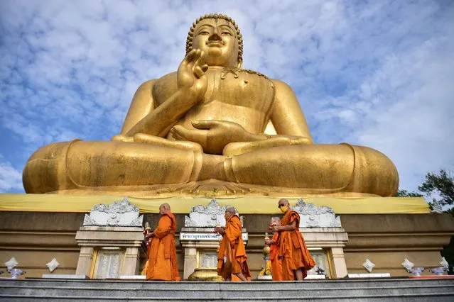 Buddhist monks walk around a giant Buddha statue as they perform religious rites to mark Makha Bucha Day in the southern Thai town of Narathiwat on March 6, 2023. (Photo by Madaree Tohlala/AFP Photo)
