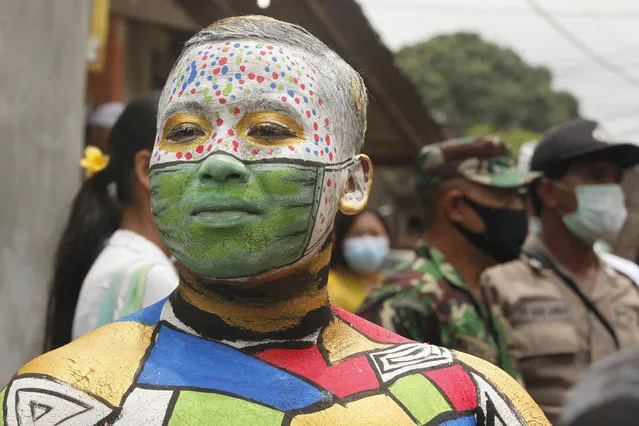 A Balinese man participates in the Hindu ritual of “Grebeg” at the Tegalalang village in Bali, Indonesia Thursday, October 22, 2020. In this biannual ritual, participants paint their bodies with colorful paint and parade around their village to ward off evil spirits. (Photo by Firdia Lisnawati/AP Photo)