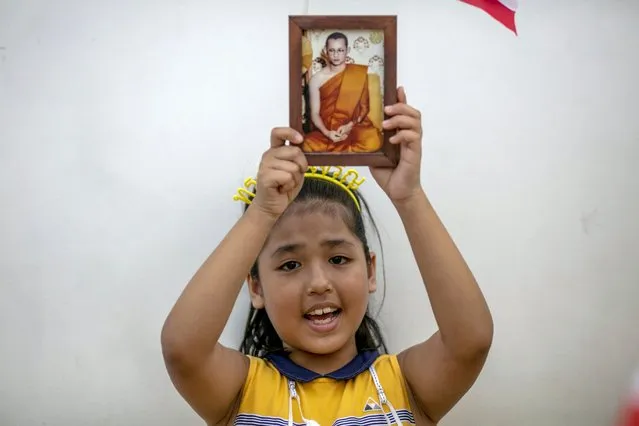 A child displays an image of late King Bhumibol Adulyadej as she gathers with adults in front of the Grand Place in Bangkok, Thailand, Sunday, November 1, 2020. Hundreds of royalists gathered close to the Grand Palace in which King Maha Vajiralongkorn is scheduled to visit for a Buddhist religious ceremony. (Photo by Wason Wanichakorn/AP Photo)