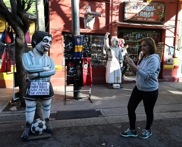 A tourist takes pictures of a figure depicting Argentine former soccer player Diego Maradona (L) near a figure of Pope Francis at Caminito, a tourist hotspot of La Boca neighborhood in Buenos Aires, Argentina, October 15, 2016. (Photo by Enrique Marcarian/Reuters)