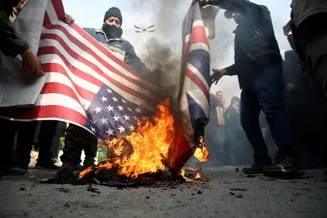 Demonstrators burn the U.S. and British flags during a protest against the killing of Soleimani in Tehran, Iran January 3, 2020. The overnight attack, authorised by President Donald Trump, was a dramatic escalation in a “shadow war” in the Middle East between Iran and the United States and its allies, principally Israel and Saudi Arabia. (Photo by Nazanin Tabatabaee/WANA (West Asia News Agency) via Reuters)