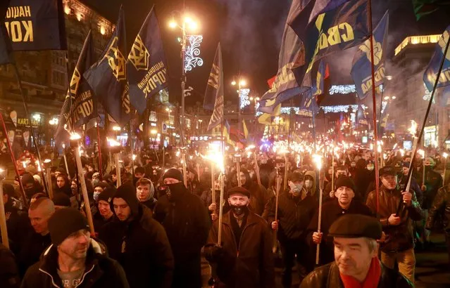 Activists and supporters of Ukrainian nationalist parties hold torches as they take part in a rally to mark the 112th birth anniversary of Stepan Bandera, one of the founders of the Organisation of Ukrainian Nationalists (OUN), in Kyiv, Ukraine on January 1, 2021. (Photo by Valentyn Ogirenko/Reuters)