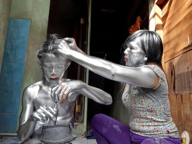Puryanti, a 29-year-old woman, and her 15-year-old nephew Raffi, cover themselves from head to toe in silver paint to become “manusia silver” (silver people), as part of their act to make a living, in Depok, on the outskirts of Jakarta, Indonesia, February 6, 2021. (Photo by Adi Kurniawan/Reuters)