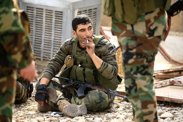 A member of Peshmerga forces smokes in the town of Bashiqa, after it was recaptured from the Islamic State, east of Mosul, Iraq, November 9, 2016. (Photo by Thaier Al-Sudani/Reuters)