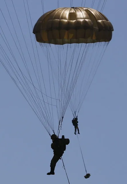 Japanese Ground Self-Defense Force's 1st Airborne Brigade soldiers parachutes down from a CH-47 helicopter during their military drill at Higashifuji training field in Susono, west of Tokyo, July 8, 2013. Japan faces increasingly serious threats to its security from an assertive China and an unpredictable North Korea, a defence ministry report said on Tuesday, as ruling politicians call for the military to beef up its ability to respond to such threats. (Photo by Issei Kato/Reuters)