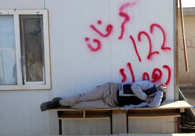 A displaced man sleeps on the table at a school used as a shelter in Bawiza, north of Mosul, Iraq November 13, 2016. (Photo by Ari Jalal/Reuters)