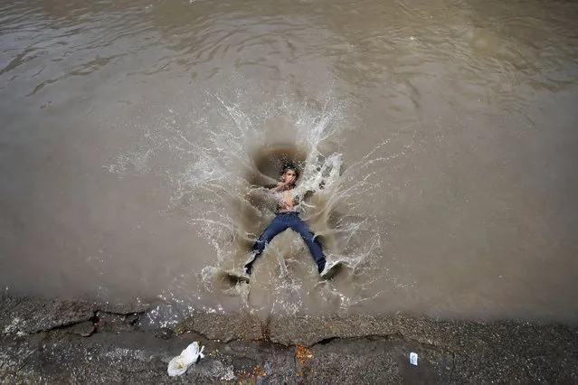 A boy jumps into a canal on a hot day in Jammu, India, Tuesday, June 20, 2023. Many parts of India are experiencing scorching heat this summer. (Photo by Channi Anand/AP Photo)