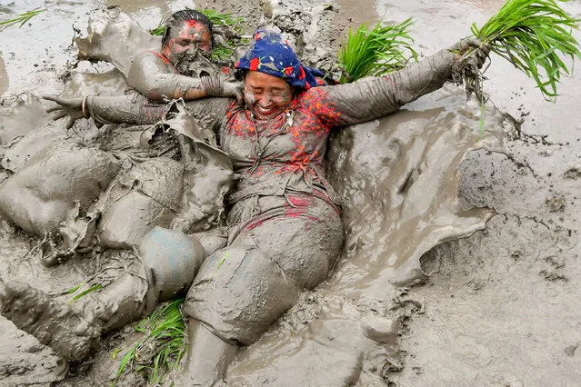 Mud-covered farmers play in a paddy field during “National Paddy Day”, which marks the start of the annual rice planting season, in Tokha village on the outskirts of Kathmandu on June 30, 2023. (Photo by Prakash Mathema/AFP Photo)