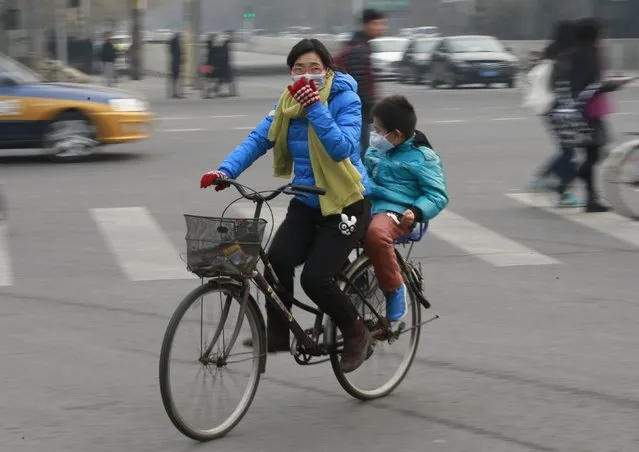 A woman an a child wearing protective masks ride a bicycle on the second day after China's capital Beijing issued its second ever “red alert” for air pollution, in Beijing, China, December 20, 2015. (Photo by Kim Kyung-Hoon/Reuters)