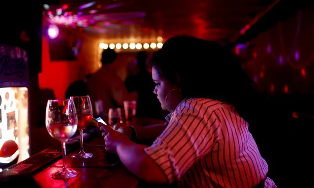 A bartender uses her cellphone in a bar during the 2018 soccer World Cup in St. Petersburg, Russia, Monday, July 9, 2018. (Photo by Natacha Pisarenko/AP Photo)