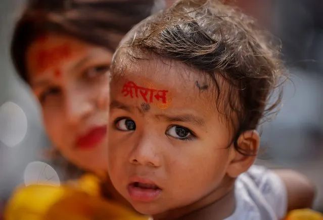 A Hindu pilgrim carries her son, with Lord Ram's name written on his forehead, as they visit the Ram Temple construction site in Ayodhya in India on July 9, 2023. (Photo by Adnan Abidi/Reuters)