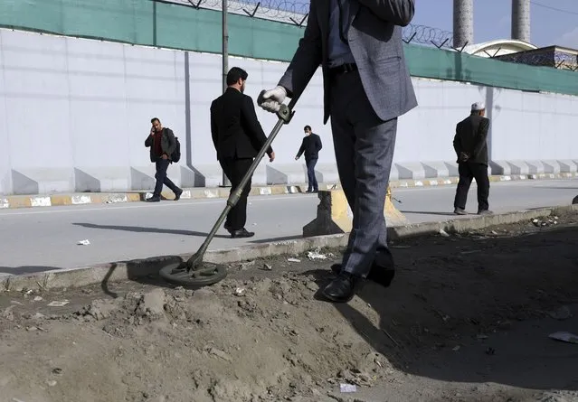 An Afghan security official looks for mines or improvised explosive device with metal detector on a roadside during a trip organized by the police for The Associated Press, in Kabul, Afghanistan, March 17, 2021. Sticky bombs slapped onto cars trapped in Kabul’s chaotic traffic are the newest weapons terrorizing Afghans in the increasingly lawless nation. The surge of bombings comes as Washington searches for a responsible exit from decades of war. (Photo by Rahmat Gul/AP Photo)