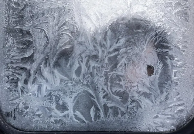 A woman looks through an icy window in a bus in  Vilnius, Lithuania, Wednesday, January 6, 2016. The air temperature was -23 degrees Celsius (-9.4 degrees Fahrenheit). (Photo by Mindaugas Kulbis/AP Photo)