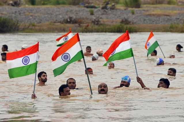 People hold India's national flags as part of the “Akhand Sankalp Tiranga Yatra” in Narmada river on the eve of country's Independence Day celebrations in Jabalpur on August 14, 2023. (Photo by Uma Shankar Mishra/AFP Photo)