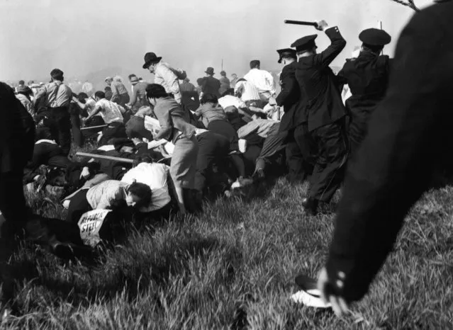 In this May 30, 1937 file photo, police using guns, clubs and tear gas advance into marching strikers outside Chicago's Republic Steel plant during violent clashes in the early days of labor union organizations. (Photo by Carl Linde/AP Photo)