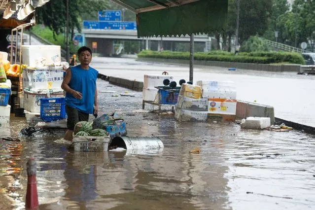 A man stands on a flooded road in Hong Kong on September 8, 2023. (Photo by Bertha Wang/AFP Photo)
