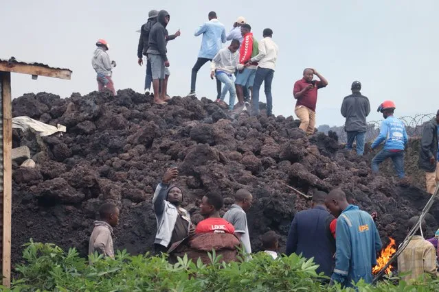 People gather on a stream of cold lava rock following the overnight eruption of Mount Nyiragongo in Goma, Congo, Sunday, May 23, 2021. Witnesses say Congo’s Mount Nyiragongo volcano unleashed lava that destroyed homes on the outskirts of Goma but the city of nearly 2 million was mostly spared after the nighttime eruption. Residents of the Buhene area said many homes had caught fire as lava oozed into their neighborhood. (Photo by Justin Kabumba/AP Photo)