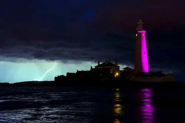 Lightning is seen behind St Mary's Lighthouse, Whitley Bay, North Tyneside, on October 25, 2013. (Photo by Steve Drew/PA Wire)