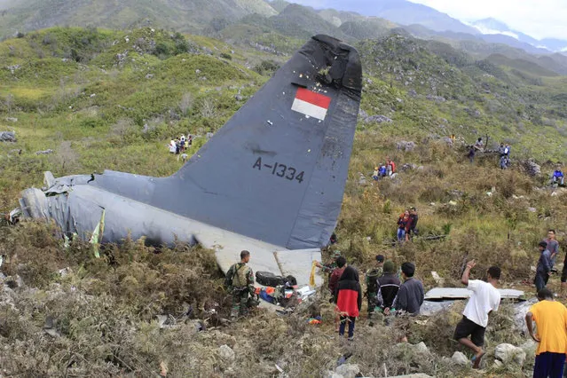 Rescuers collect personal belongings of the victims of an Indonesian Air Force plane that crashed in the mountainous area in Wamena, Papua province, Indonesia Sunday, December 18, 2016. The Hercules C-130 transport plane crashed in bad weather in the easternmost province, killing all people on board. (Photo by Gerry Kossay/AP Photo)