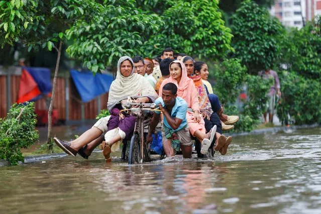 Commuters ride on a rickshaw on a flooded road after heavy rains in Dhaka, Bangladesh on September 22, 2023. (Photo by Mohammad Ponir Hossain/Reuters)