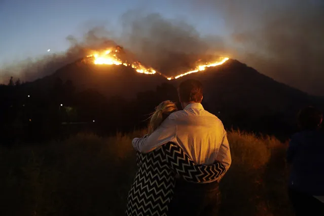 Roger Bloxberg, right, and his wife Anne hug as they watch a wildfire on a hill top near their home Friday, November 9, 2018, in West Hills, Calif. (Photo by Marcio Jose Sanchez/AP Photo)