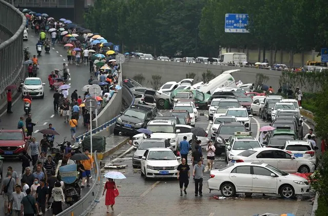 People look at cars sitting in floodwaters following heavy rains, in Zhengzhou in China's central Henan province on July 22, 2021. (Photo by Noel Celis/AFP Photo)