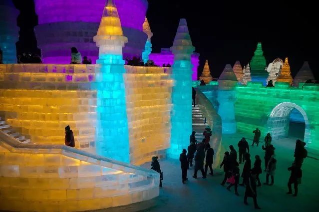 People visit ice sculptures illuminated by coloured lights at the Harbin Ice and Snow Festival to celebrate the new year in Harbin on January 5, 2017. (Photo by Nicolas Asfouri/AFP Photo)