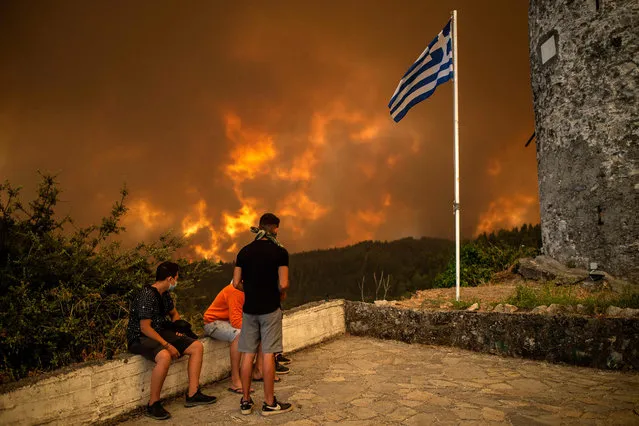 Local residents look at the wildfire approaching the village of Gouves on Evia (Euboea) island, second largest Greek island, on August 8, 2021. Hundreds of Greek firefighters fought desperately on August 8 to control wildfires on the island of Evia that have charred vast areas of pine forest, destroyed homes and forced tourists and locals to flee. (Photo by Angelos Tzortzinis/AFP)