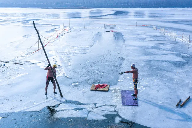 This photo taken on December 5, 2023 shows two winter swimmers moving chunks of ice to create an area for swimming at a lake in Shenyang, in China’s northeastern Liaoning province. (Photo by AFP Photo/China Stringer Network)
