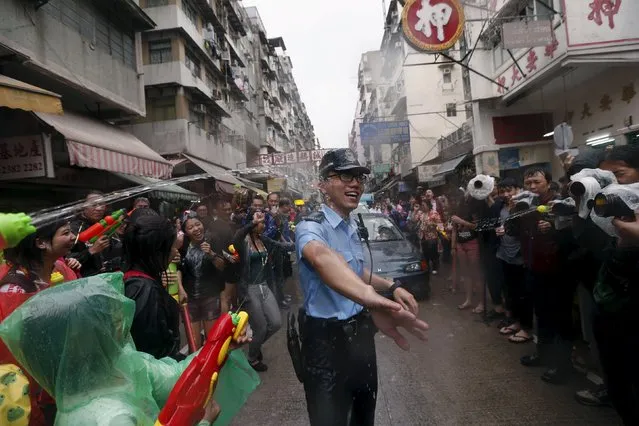 A police officer gets sprayed by water guns during Songkran Festival celebrations at Kowloon City district, known as Little Thailand as there is large number of restaurants and shops run by Thais, in Hong Kong April 12, 2015. (Photo by Tyrone Siu/Reuters)