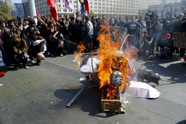 Protesters burn an effigy depicting Chile's President Michelle Bachelet, in front of the government palace during a demonstration to demand changes in the education system at Santiago, April 16, 2015. (Photo by Ivan Alvarado/Reuters)